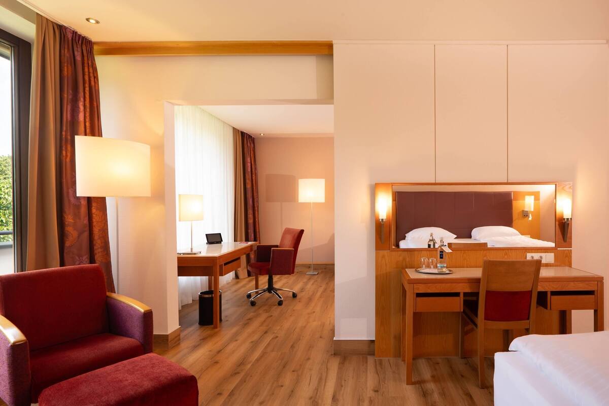 Une chambre d’hôtel avec un lit, un bureau, des chaises et une lampe.