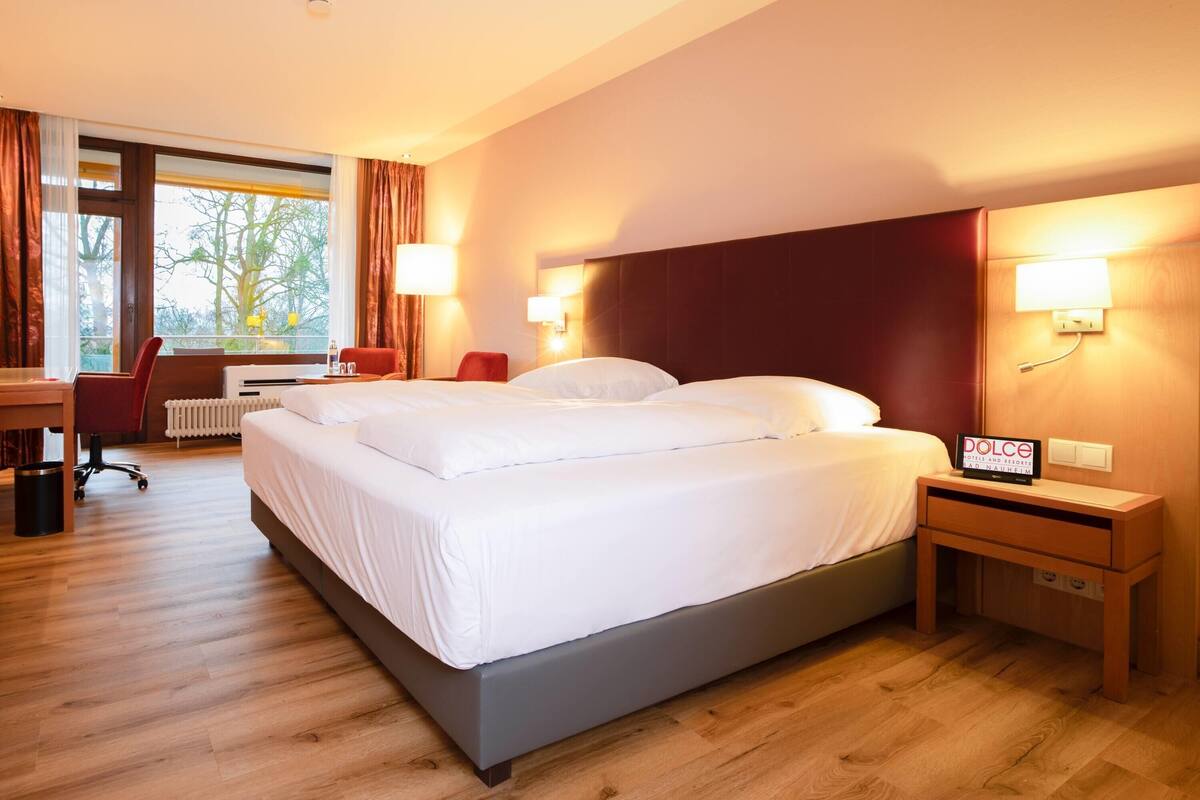 Une chambre d’hôtel avec un lit, des tables de chevet, un bureau et une chaise.