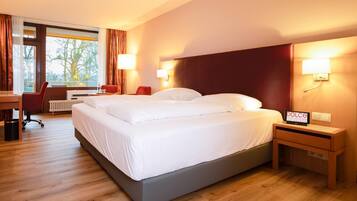 Ein Hotelzimmer mit Bett, Nachttischen, einem Schreibtisch und einem Sessel.