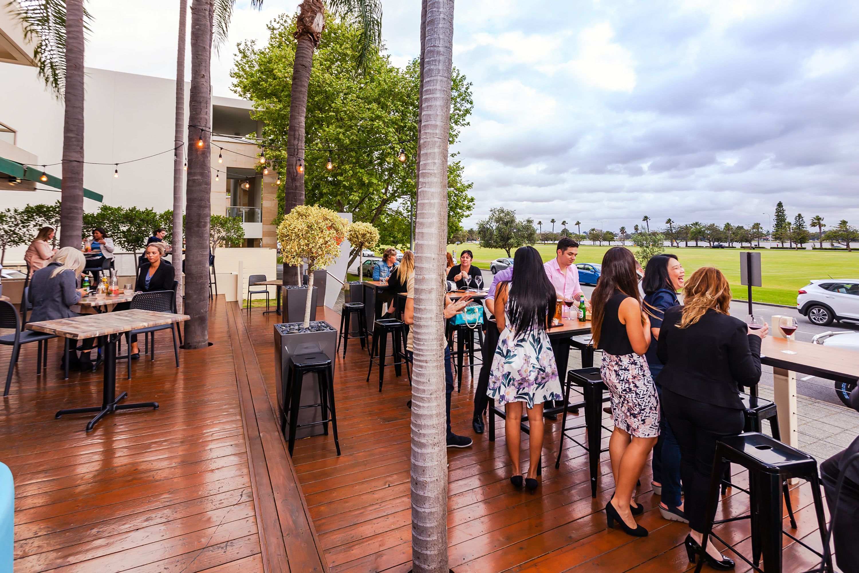 An outdoor patio area with wooden flooring, tables, and chairs.