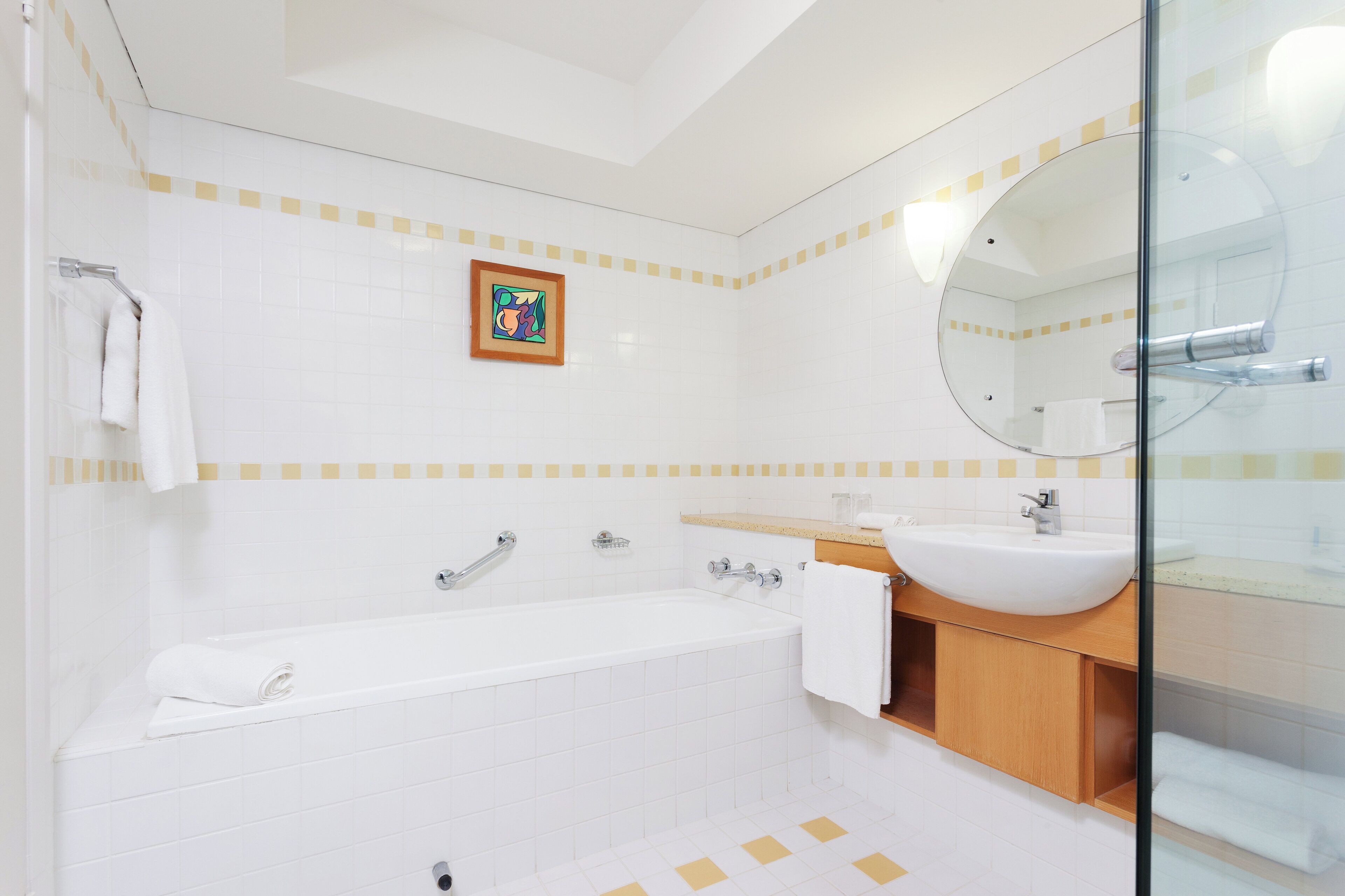 Un baño moderno con una bañera, un lavabo, un espejo y un cuadro en la pared.