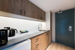 A modern kitchen with wooden cabinets, a stainless steel sink, and a coffee maker.