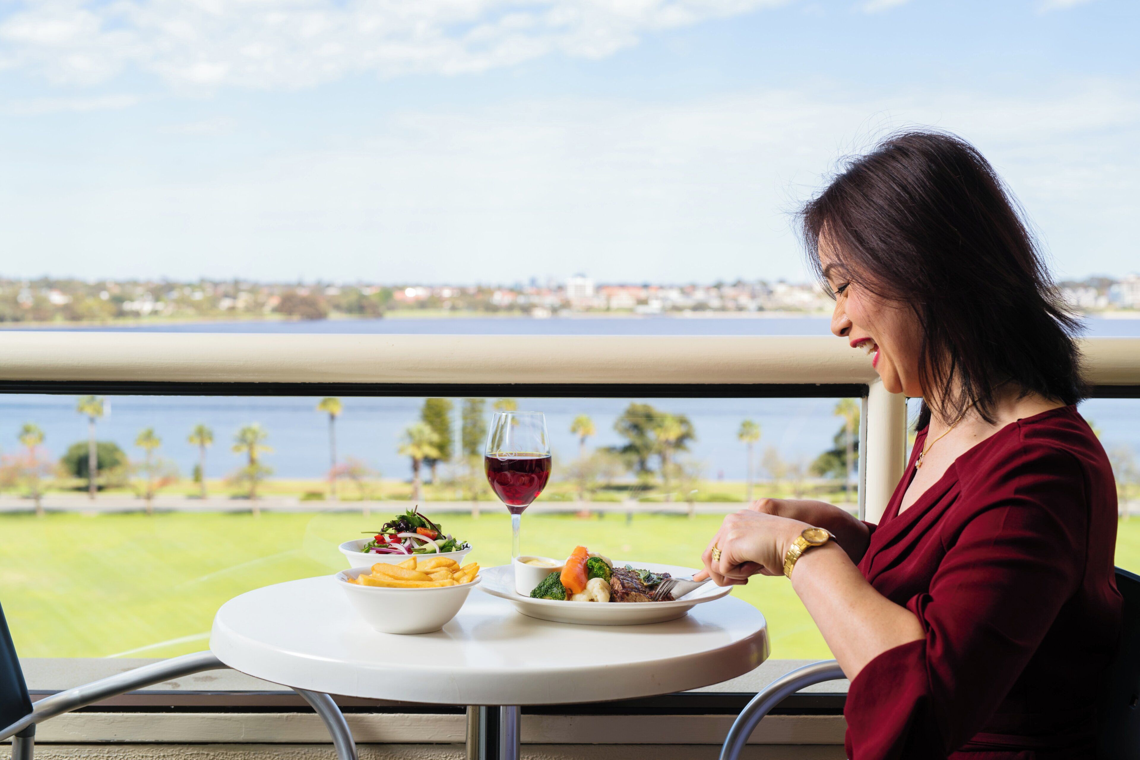 Una persona cenando en una mesa con vistas al agua y al paisaje urbano.
