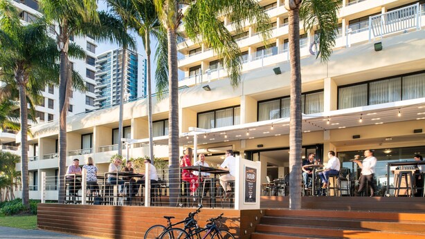 A hotel with outdoor seating, palm trees, and a bike parked outside. - Crowne Plaza Perth by IHG (East Perth)