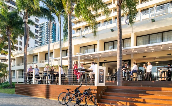 A hotel with outdoor seating, palm trees, and a bike parked outside. - Crowne Plaza Perth by IHG (East Perth)