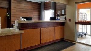 A reception desk with a wooden finish, a digital screen, and a fire safety sign. - Wingate by Wyndham Great Falls (Great Falls)