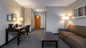 A hotel room with a desk, office chair, sofa, and a lamp. - Wingate by Wyndham Great Falls (Great Falls)