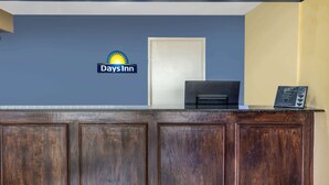 Una recepción con el logotipo de Days Inn, una puerta cerrada y un pequeño letrero en el mostrador.