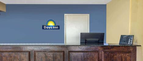 Una recepción con el logotipo de Days Inn, una puerta cerrada y un pequeño letrero en el mostrador.