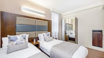 Une chambre d’hôtel avec deux lits, une tête de lit en bois, un miroir et une armoire.
