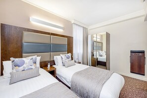 Ein Hotelzimmer mit zwei Betten, einem Holz-Kopfteil, einem Spiegel und einem Kleiderschrank.
