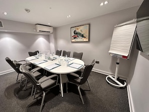 A conference room with a round table, chairs, a whiteboard, and a framed picture on the wall. - Mercure London Paddington (London)