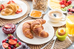 A breakfast setting with croissants, strawberries, blueberries, a croissant in a cup, a cup of coffee, and a glass of orange juice. - Mercure London Paddington (London)
