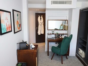 A hotel room with a desk, chair, artwork, a minibar, a mirror, and a wardrobe. - Mercure London Paddington (London)