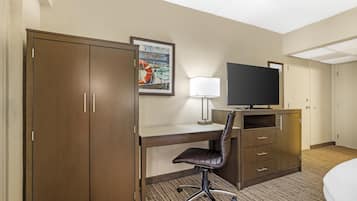 Une chambre d’hôtel équipée d’un bureau, d’une chaise, d’une télévision, d’une armoire et d’un lit.