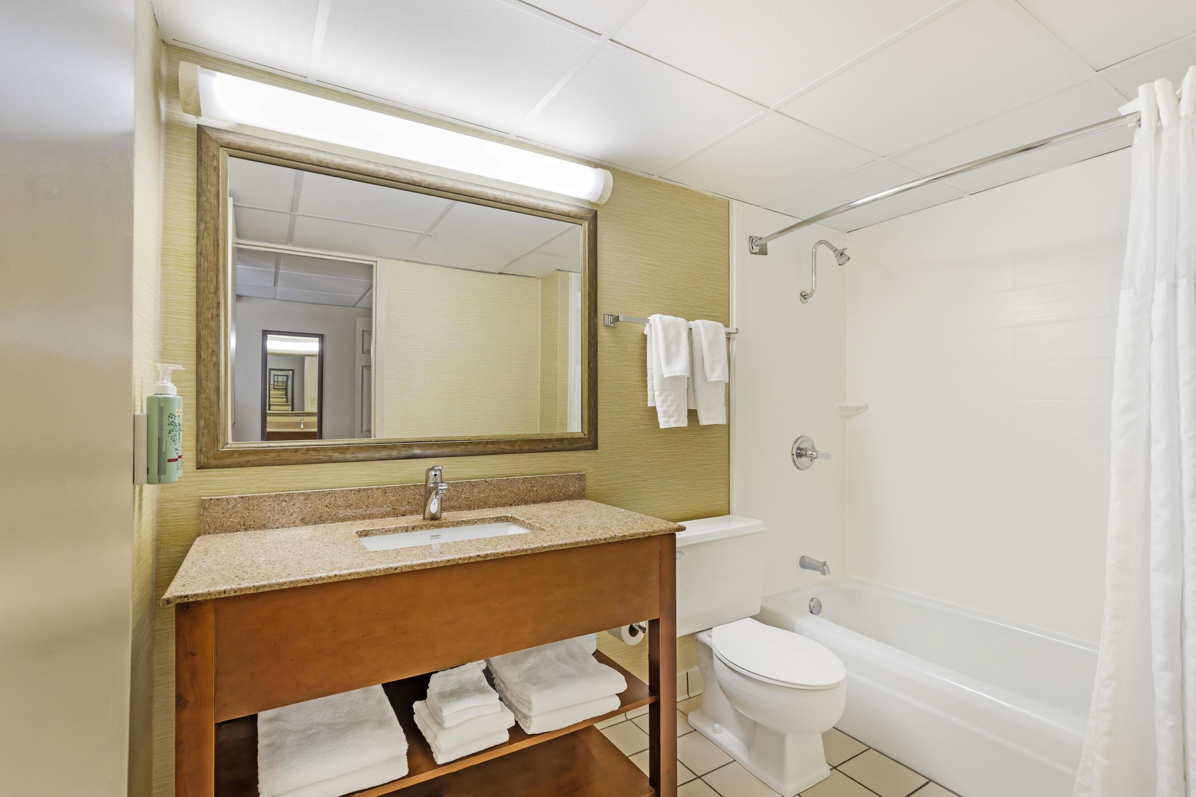 A bathroom with a sink, mirror, towel rack, toilet, and bathtub.
