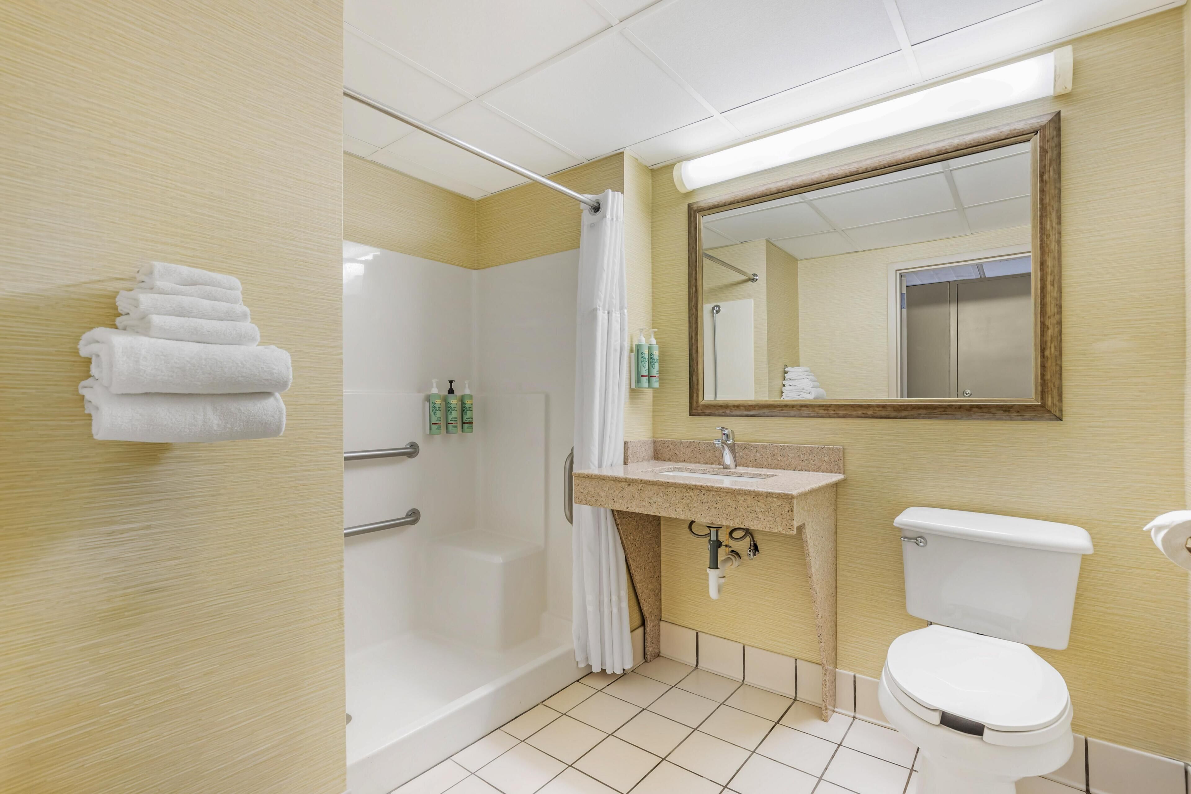 A bathroom with a bathtub, toilet, sink, and a mirror.
