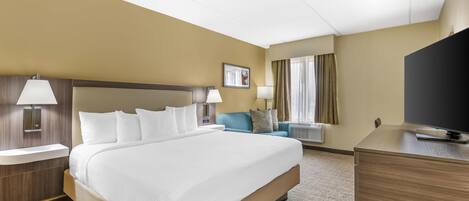 Una habitación de hotel con una cama grande, televisión, escritorio y sofá.