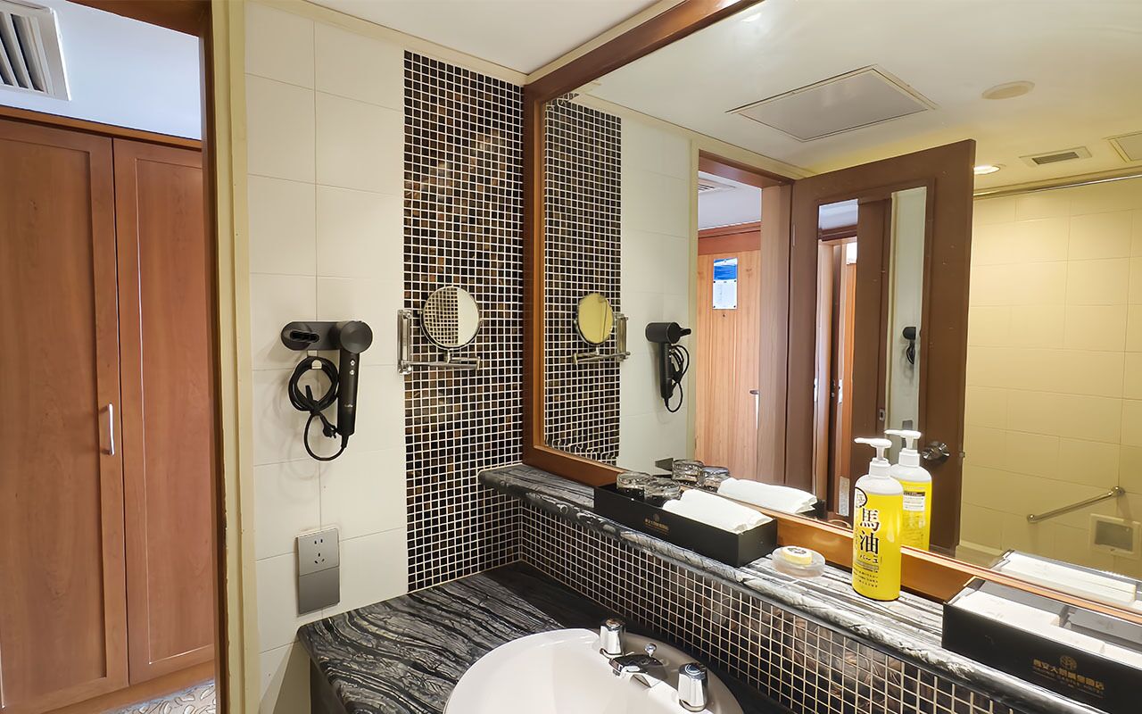 A bathroom with a large mirror, two hair dryers, a sink, and a toilet.