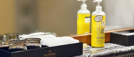 A bathroom vanity with toiletries, a black box with a logo, and a mirror.