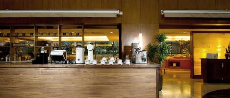 A modern hotel lobby with a wooden reception desk, a large window, and a view of the outdoors.