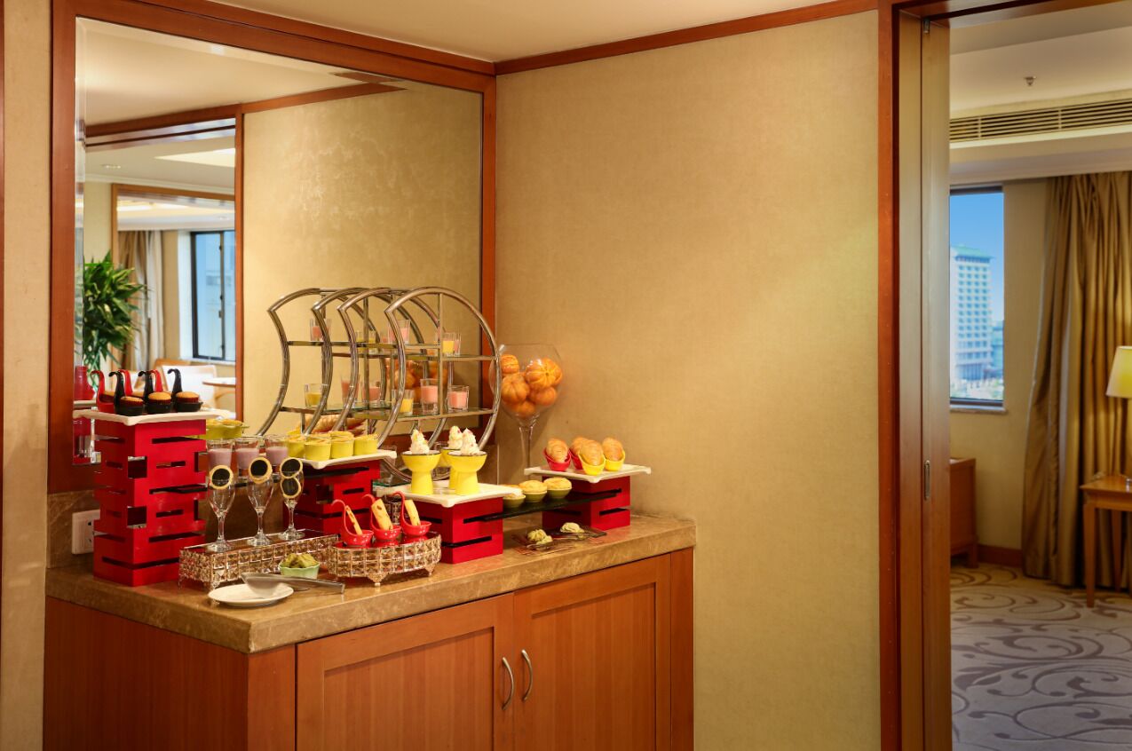 Hotelkamer met een ontbijtbalk, een schaal fruit, een koffiehoek en een glazenhouder.