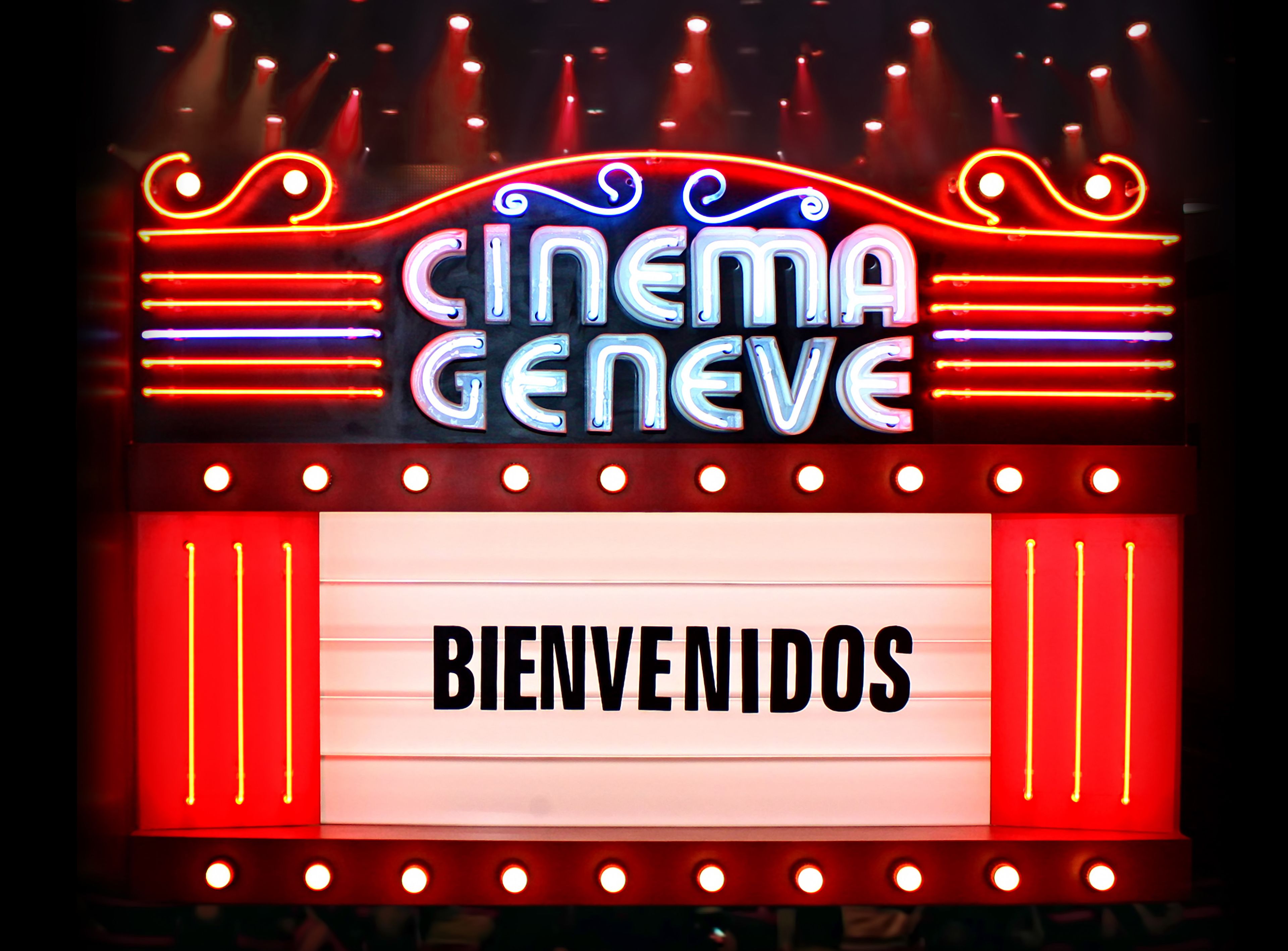 Ein Neonzeichen mit der Aufschrift "CINEMA GENEVE" und "BIENVENIDOS", das ein Willkommenszeichen für ein Kino andeutet.