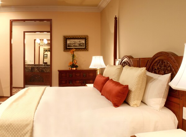 Una habitación de hotel con una cama grande, un aparador, un espejo y un cuadro en la pared.
