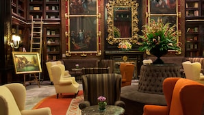 A library with bookshelves, a fireplace, and a variety of seating including armchairs and a sofa.
