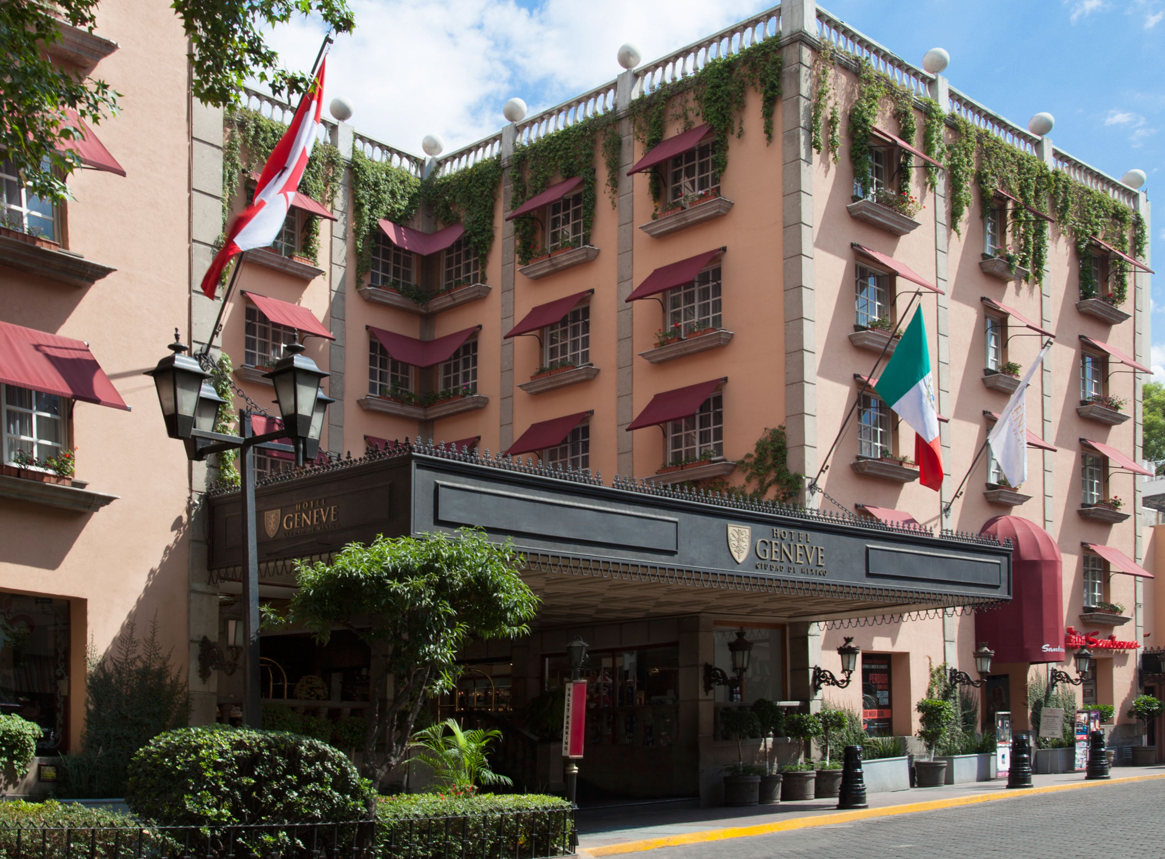 Fachada de un hotel con varios balcones, banderas y un cartel que indica su nombre.