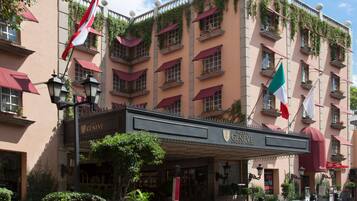 Fachada de un hotel con varios balcones, banderas y un cartel que indica su nombre.