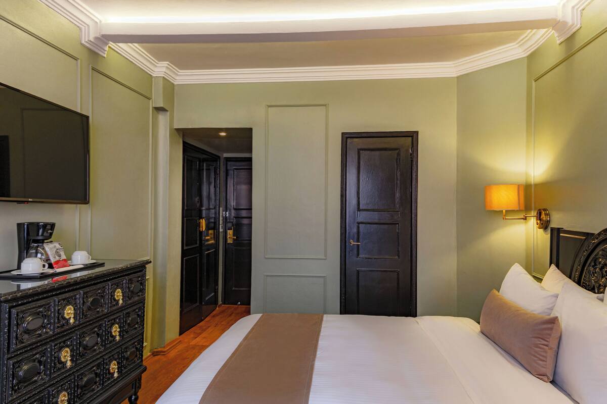 Une chambre d’hôtel avec un lit, une commode et un téléviseur.