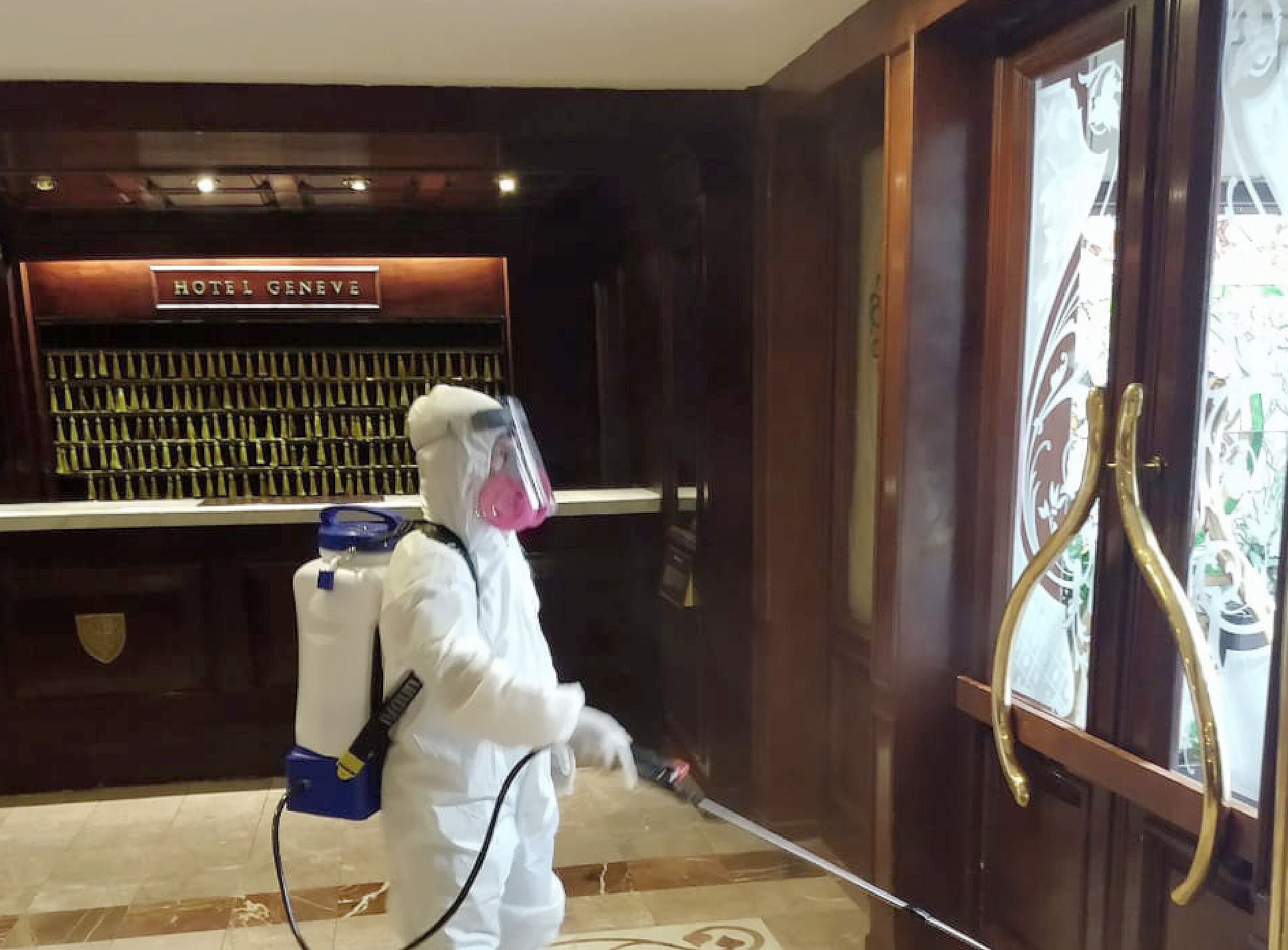 A person in a white protective suit spraying a room.