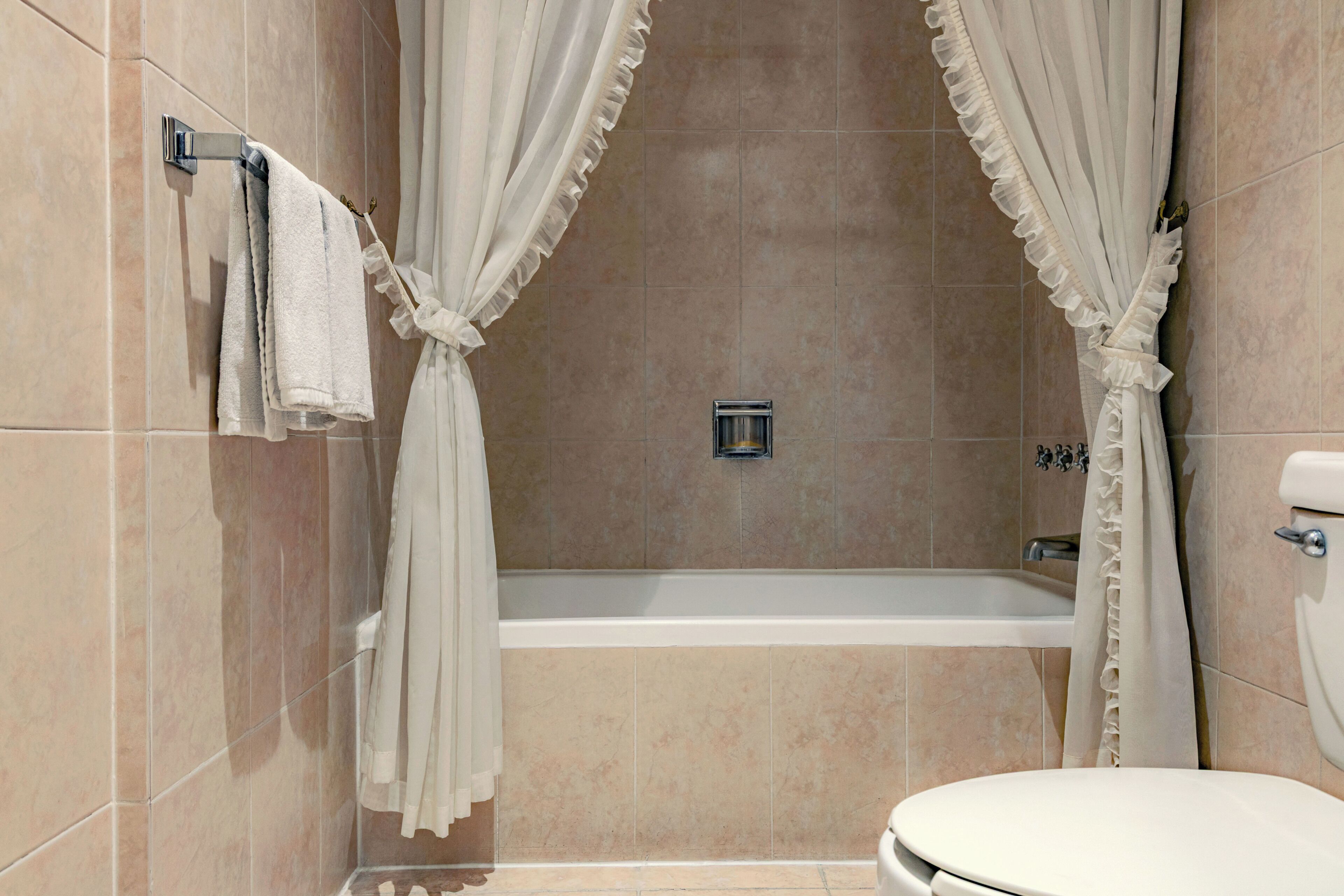 Un baño con bañera, inodoro y toallero.