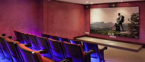 A theater with rows of seats and a large screen displaying a movie scene.