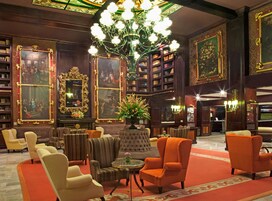 Un vestíbulo imponente con candelabros elaborados, asientos lujosos y amplias colecciones de libros.