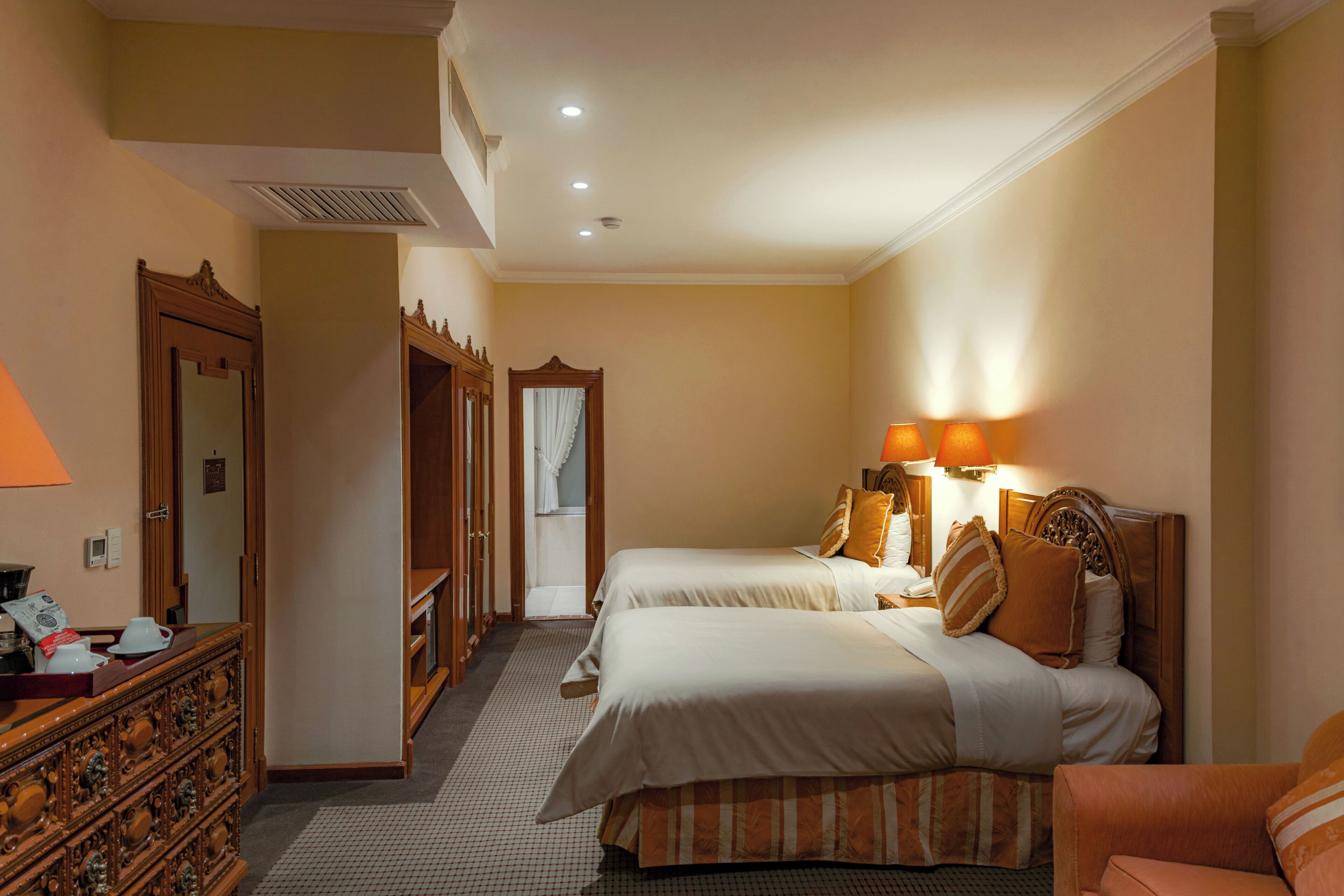 Habitación de hotel con dos camas, un aparador, un espejo y una lámpara.