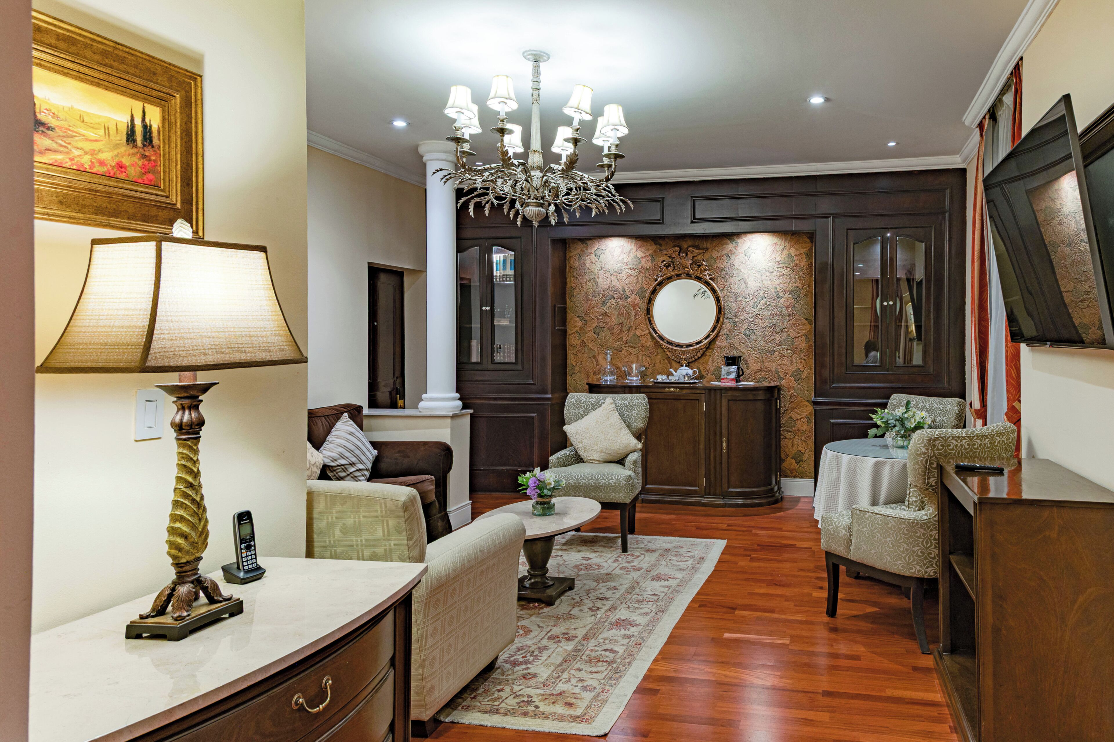 A well-furnished living room with a chandelier, comfortable seating, a coffee table, and a decorative mirror.