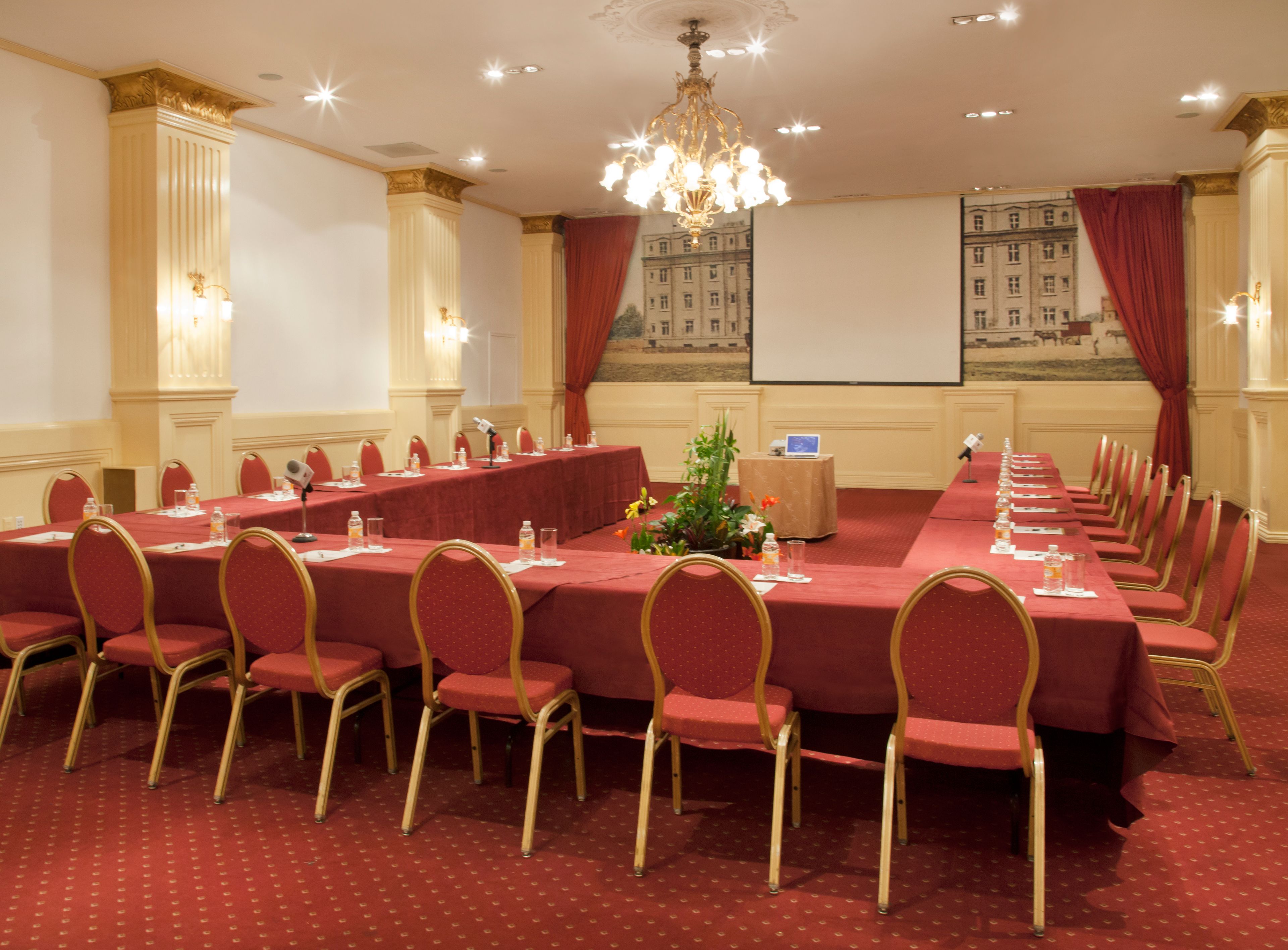 A conference room with a long table, red chairs, and a chandelier.