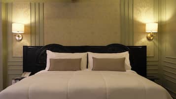 A hotel room with a large bed, two wall-mounted lamps, and a telephone on the nightstand.