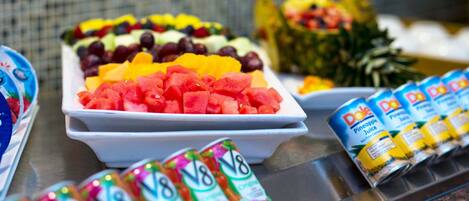A buffet with various fruits and canned drinks.