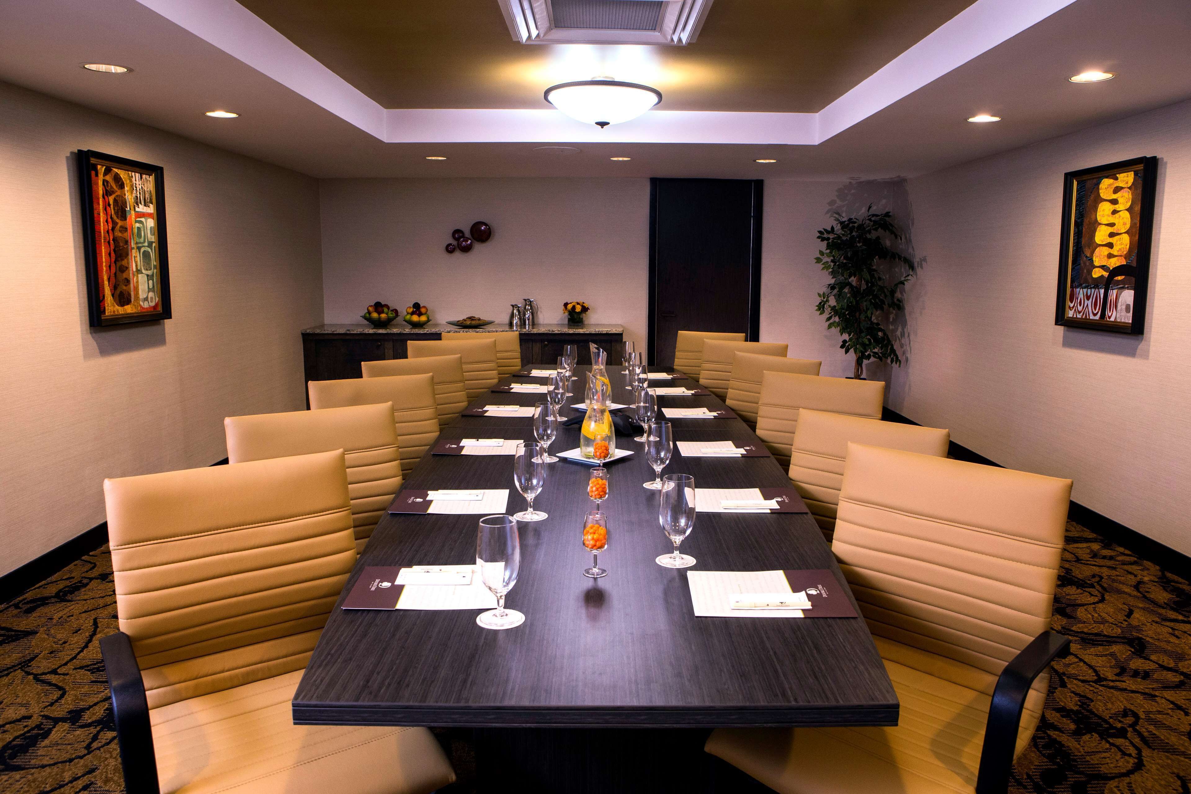 A conference room with a long table, beige chairs, and a dark wooden table.