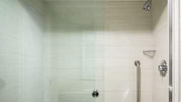 Una ducha moderna con puerta de vidrio, cabezal de ducha de mano y control manual.