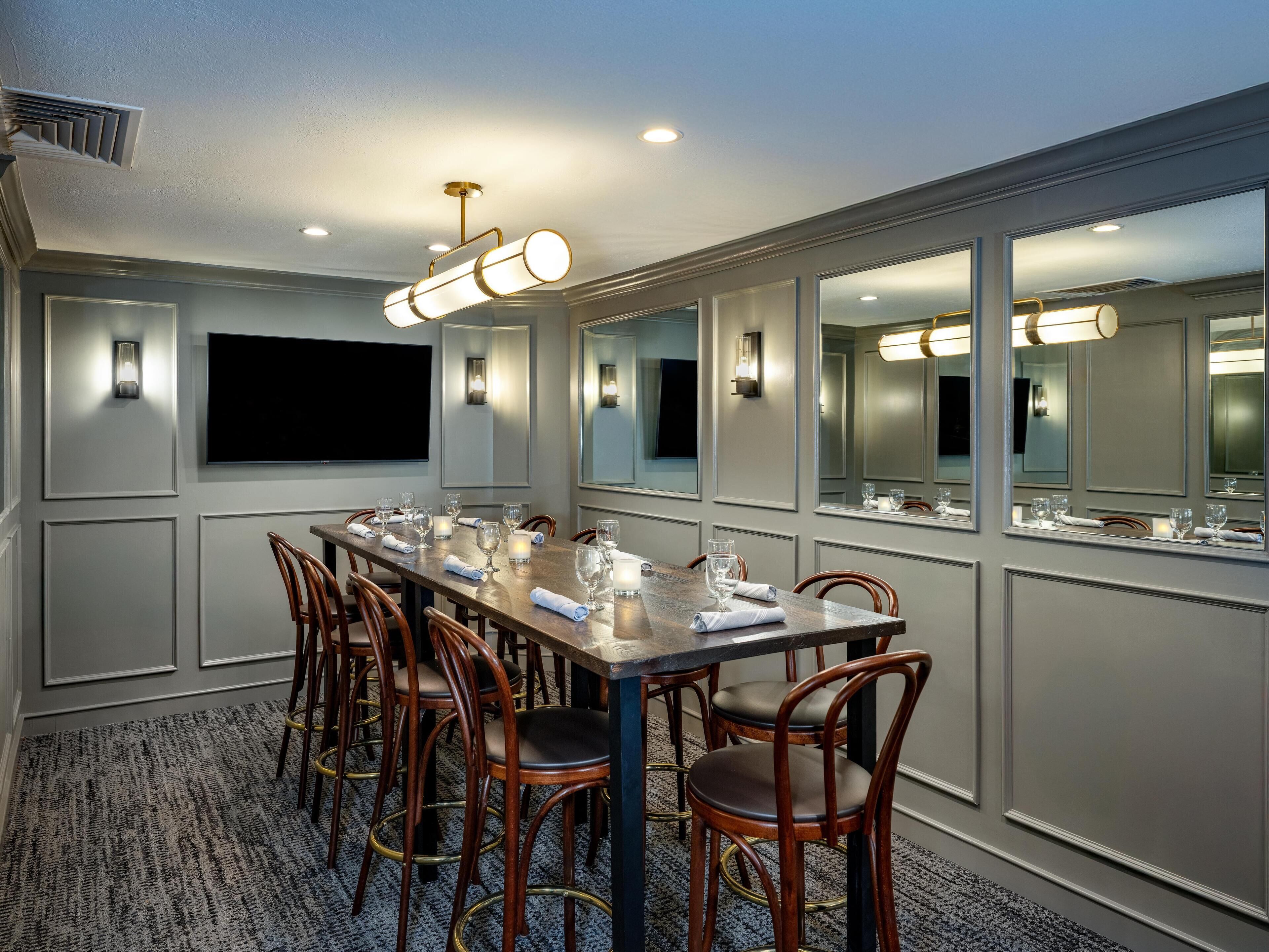 A conference room with a long table, chairs, and a flat-screen TV.
