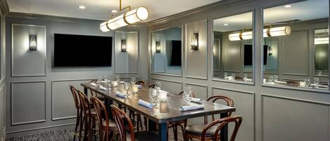 A conference room with a long table, chairs, and a flat-screen TV.
