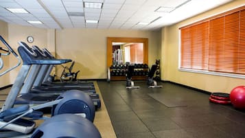 Een sportschool met loopbanden, gewichten en fitnessballen.