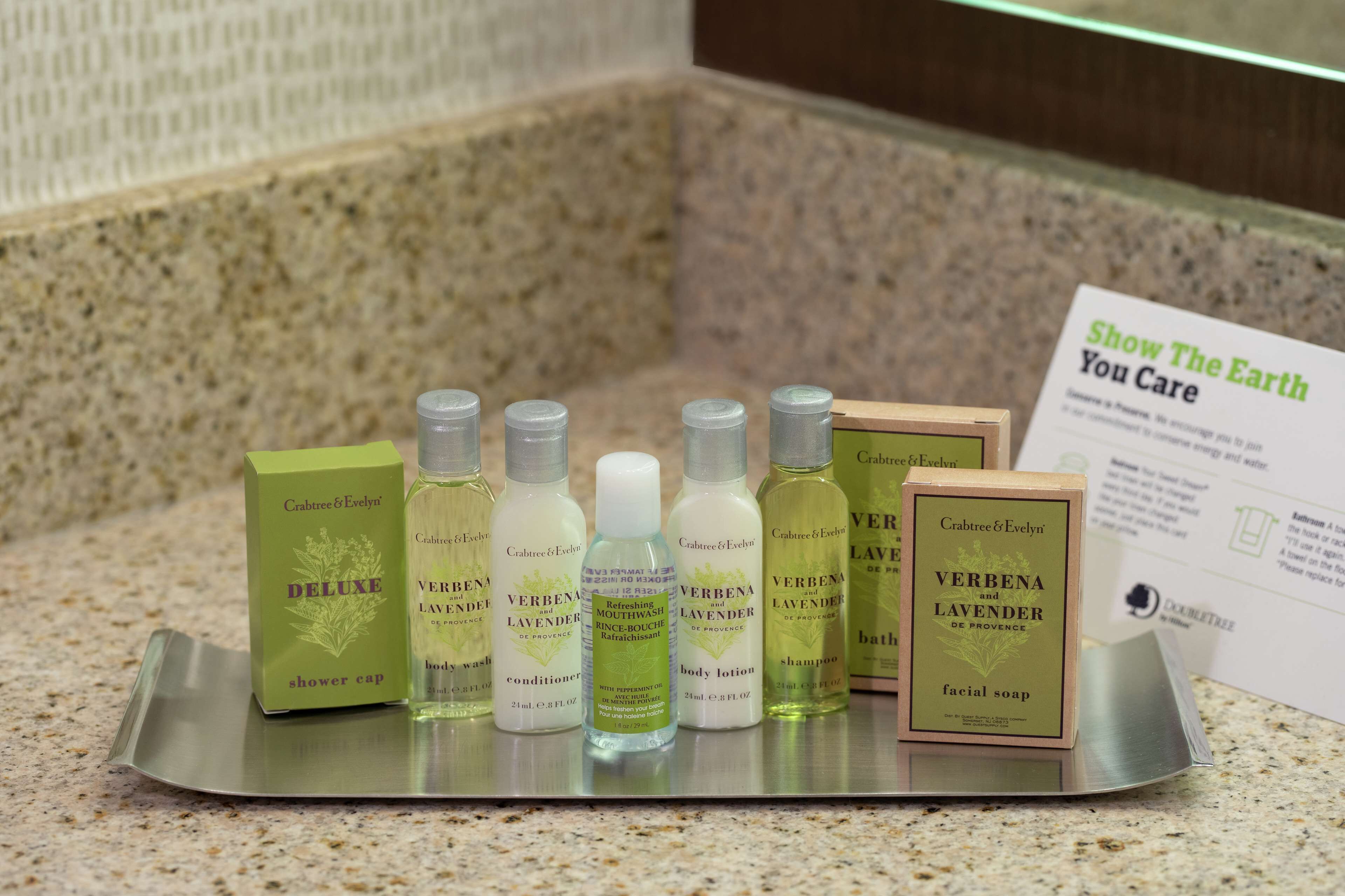 Un plateau contenant différentes bouteilles de produits Crabtree & Evelyn, notamment un bonnet de douche, un après-shampoing, une lotion pour le corps, un shampoing et un savon pour le visage.