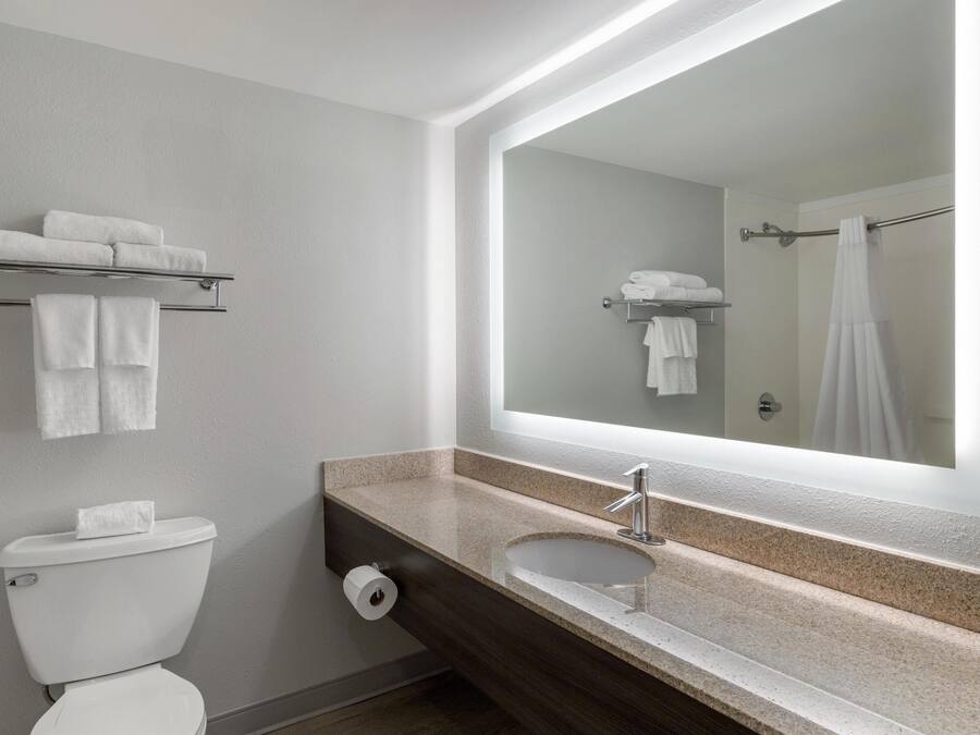 A modern bathroom with a toilet, sink, and towel racks.