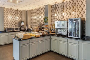 A breakfast bar with microwaves, a coffee machine, and a refrigerator.