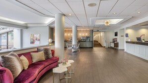 A modern hotel lobby with a red velvet sofa, white tables, and a reception desk. - Best Western Hickory (Hickory)